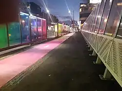 colourful rainbow fencing and bus shelters on Grafton Bridge lit at night