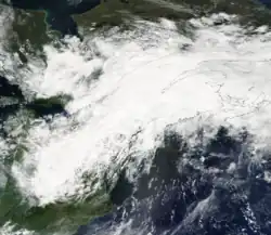 A satellite image of an extended area of clouds oriented southwest to northeast across the Great Lakes region of the United States and Canada