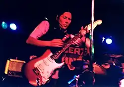 Kim Deal playing electric guitar onstage in 1995