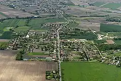 An aerial photo of Kisigmánd, a small village. The village is centred along a central road.