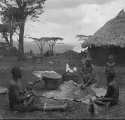 Gusii women thrashing corn with children watching c. 1916–1938.