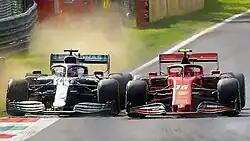 Leclerc racing against Lewis Hamilton at the 2019 Italian Grand Prix, with dirt being kicked up by Hamilton's tyres, who is partially off-track