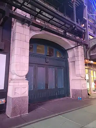 The former entrance to the Liberty Theatre on 42nd Street. It consists of a set of green doors within a stone archway. There is an electronic sign above the door.