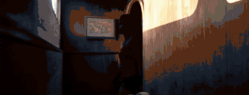 A screenshot of Man of Medan's premonitions mechanic. The player character walks into a room, where a black-framed picture hangs on a wall. A button prompt with a green "A" on the centre appears beside the picture to indicate that the player can interact with it. Once the button is pressed, the game shows a vision of a character, Conrad, getting away from the other characters using a speedboat.