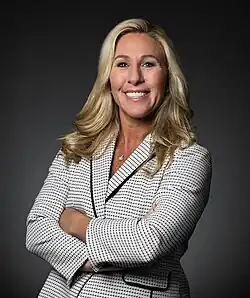 Greene smiling and standing in a grayish black background