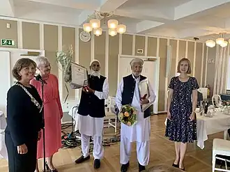 Several people gathered together. Rafiq and Iqbal, standing in the middle, holds their medals