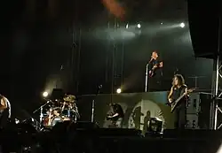 The four band members are shown performing during a concert