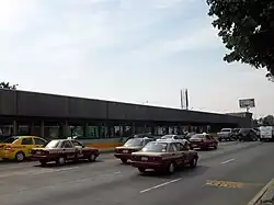 Picture of the station in the middle of Río Consolado Avenue. Several automobiles surround the station.