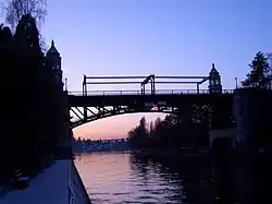 A bridge with Collegiate Gothic style towers over a canal at sunset