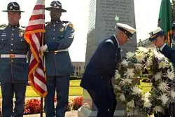 Coast Guard officers lay a wreath at the Medal of Honor memorial in Olympia, Washington. A Washington State Patrol color guard is present.