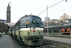 An older locomotive with the Northern Pacific Railway logo (a yin-yang roundel) parked at a train station with a prominent clocktower and several empty platforms.