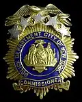 A modified version of the shield and supporters on the badge of the city police commissioner