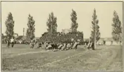 Men lined up in dark sweaters preparing for the beginning of a football play