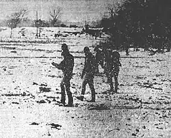 Five police officers walking in a line looking at snow-covered ground