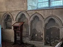The piscina (left of wooden lectern) and sedilia in St. Mary's church, Buriton, Hampshire