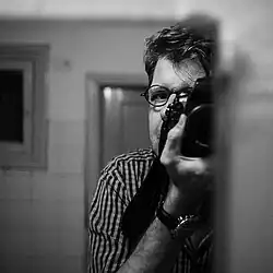 An artistic self portrait of a man photographing himself in a mirror