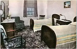 Two small beds in a small room with a dresser and two windows