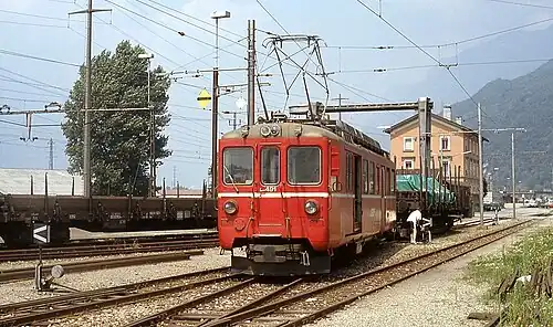 Red locomotive with three-story building in background