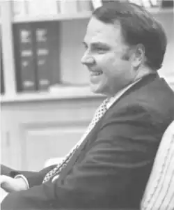 A man in a sportcoat and tie, seated