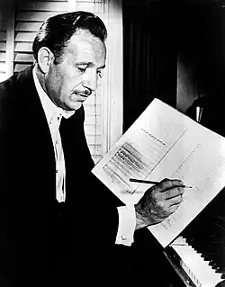 A man seated at a piano writing musical notation