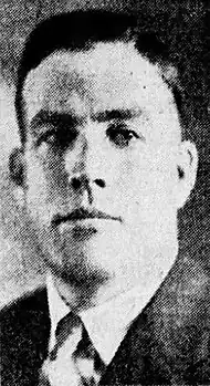 Black and white photo of a middle-aged man wearing a dark-coloured suitcoat and a white high-collar dress shirt