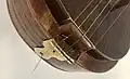 The strings are tied off in a loop and anchored on the metal plate at the bottom. the top string is set slightly apart from the 4 drone strings, and is elevated higher above the finger board as well.