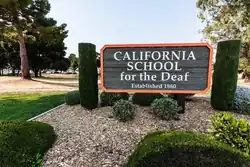 Wood sing with orange outlinging stating "California School for the deaf" Fremont