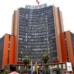 A tall building forming a semicircle with many windows and orange on its narrow sides.