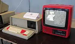 A computer in a red case with a separate monitor and keyboard. The monitor is displaying a vector graphic of a wave.