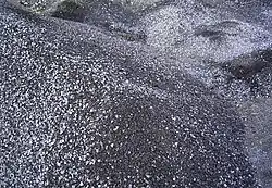 A photograph of dark gray/silver piles of spent shale lumps.