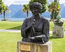 Bronze statue of Fitzgerald in a park. She is depicted as holding a microphone and gesturing the other hand forward.