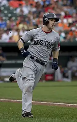 A baseball player wearing a gray uniform and black helmet runs the bases.
