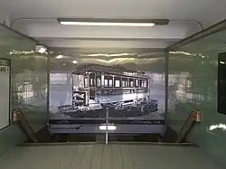 Interior of a subway entrance, with a mural of a streetcar on a reflective panel