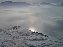 A rounder subsun, partially obstructed by a gradual mountain peak