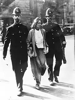 A woman under arrest walking between two policemen