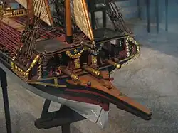 The bow of a ship model focused on a raised platform with cannons underneath