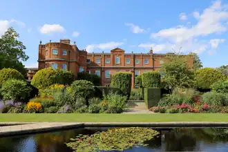 red brick stately home surrounded by parkland
