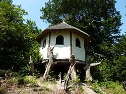 A colour photograph of a thatched hut with white walls