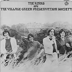 A black-and-white photo depicting the four band members smiling while standing in long grass, set against trees and Kenwood House far off in the background