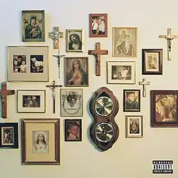 A white wall displaying various Christian paraphernalia and images of young Scrim and Ruby. A small portrait of them with the album title written below is displayed in the middle.