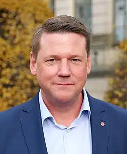 Tobias Baudin standing beside a mural depicting Dawit Isaak with "free dawit" written below