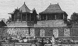 Two rectangular stone tombs, each topped with a small decorative wooden house