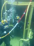 US Navy divers descending to a wreck to recover petroleum from a sunken ship.