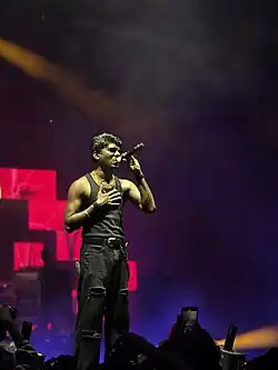 The rapper is on stage holding a microphone