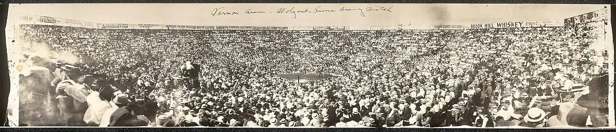 Panoramic photo of Wolgast–Rivers boxing match, July 4, 1912: "There are thousands in Los Angeles who saw Ad Wolgast fight Joe Rivers in a never-to-be-forgotten battle at Vernon about nine years ago when both men were knocked out in the 13th round and Wolgast staggered to his feet first and was awarded the decision." The words "Vernon Arena" were written on the print but this is actually the Vernon baseball field—Jack Doyle "used the ballpark for the really big fights (Ad Wolgast was very popular) because he could cram more bodies in more seats".