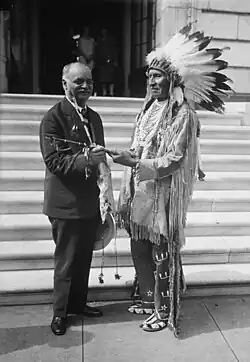 Vice President Curtis receives a peace pipe from the Lakota Red Tomahawk, slayer of Sitting Bull.