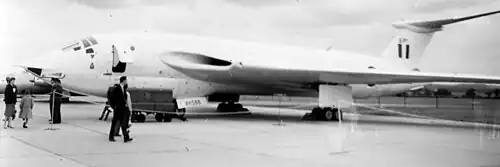 Several people walking around a jet bomber at an airfield