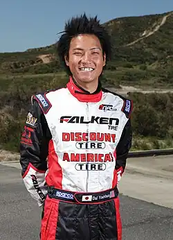 Colour photo of Dai Yoshihara smiling widely and wearing his racing gear