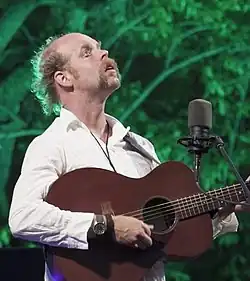 Will Oldham strums a guitar while performing live