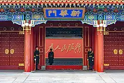 Photo of Xinhua gate (Xinhuamen/新华们) entrance in 2019 showing the slogan "为人民服务" in handwritten script